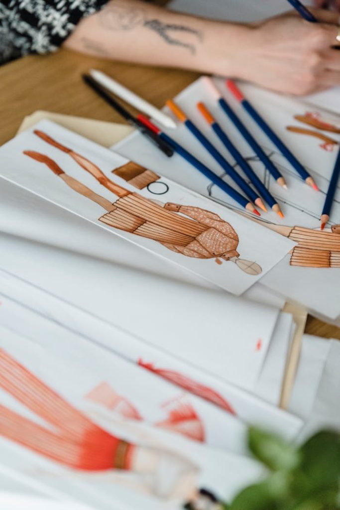 Close-up of fashion design sketches with pencils on a designers desk.